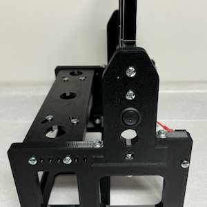 K&ouml;nnte beinhalten: Schwarzer 3D-gedruckter St&auml;nder mit einem kleinen schwarzen Schalter an der Seite. Der St&auml;nder hat mehrere L&ouml;cher und Schlitze zum Halten von Gegenst&auml;nden.