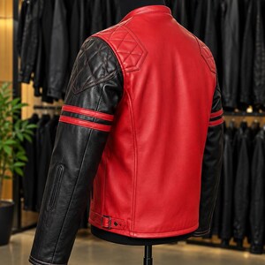 May include: A red and black leather jacket featuring a mandarin collar, quilted shoulder panels, and black sleeves with two horizontal red stripes. The jacket includes adjustable side buckles at the hem and a smooth red back panel design.
