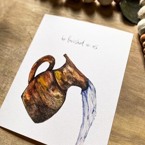 May include: A watercolor painting of a brown clay pitcher pouring out blue water. The text "he lavished on us" is written in cursive on the white background.