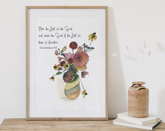 May include: A framed print with a floral arrangement in a vase. The flowers are in shades of pink, yellow, and brown. The print features the text "Now the Lord is the Spirit and where the Spirit of the Lord is, there is freedom. 2 Corinthians 3:17".
