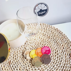 May include: A set of six colorful acrylic drink markers with a lemon slice design. Each marker has a different name written on it: Stefania, Chris, Oliver, Rita, Tyler, and Neil.