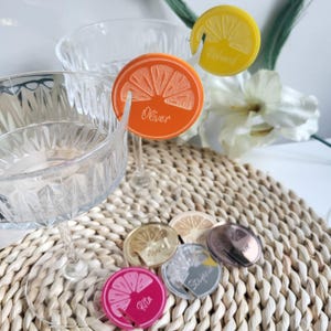 May include: Orange, pink, and gold acrylic drink markers with the names Oliver, Richard, Rita, and Sophia. The markers are shaped like orange slices and have a small hole for a straw.
