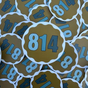 May include: A collection of round stickers with a scalloped edge. The stickers are tan with the number "814" in light blue. The number "4" is also visible on some stickers. The stickers are scattered across the image.