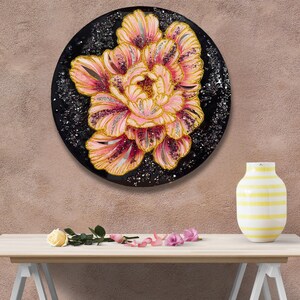 Könnte beinhalten: Runde, schwarze Wandkunst mit einer großen, stilisierten rosa-goldenen Blume. Die Blume hat mehrere Blütenblätter mit silbernen Glitzerakzenten. Ein dekoratives Wandobjekt.