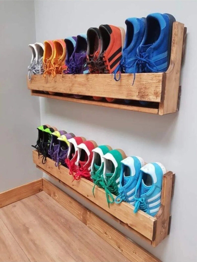 May include: A wooden shoe rack with two shelves mounted on a wall. The shelves are filled with colorful sneakers, including blue, red, green, yellow, orange, and purple.