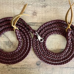 Puede incluir: Dos riendas de cuero trenzado color burdeos con correas de cuero marrón y mosquetones plateados.