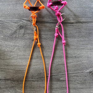 May include: Two lanyards made of neon orange and neon pink paracord, each featuring a dark brown leather tag with the word MAGIC embossed in black, a silver metal split ring, and a silver swivel lobster clasp attached to a long cord loop.