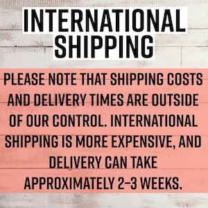 May include: A rectangular sign with a light pink background and white horizontal wood grain texture. The text reads: INTERNATIONAL SHIPPING. PLEASE NOTE THAT SHIPPING COSTS AND DELIVERY TIMES ARE OUTSIDE OF OUR CONTROL. INTERNATIONAL SHIPPING IS MORE EXPENSIVE, AND DELIVERY CAN TAKE APPROXIMATELY 2-3 WEEKS.
