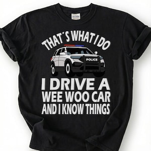 May include: Black t-shirt with the text "THAT'S WHAT I DO I DRIVE A WEE WOO CAR AND I KNOW THINGS" and a graphic of a police car. The shirt is made of a soft material.