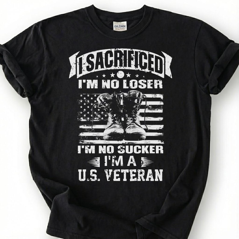 May include: Black t-shirt with a white graphic design. The design includes the word "SACRIFICED" above the text "I'M NO LOSER" and "I'M NO SUCKER I'M A U.S. VETERAN". The graphic also features combat boots and an American flag.
