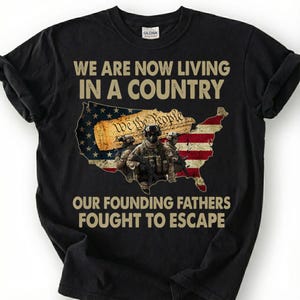 May include: Black t-shirt with the text "WE ARE NOW LIVING IN A COUNTRY OUR FOUNDING FATHERS FOUGHT TO ESCAPE." The design includes a map of the United States with the American flag and soldiers.