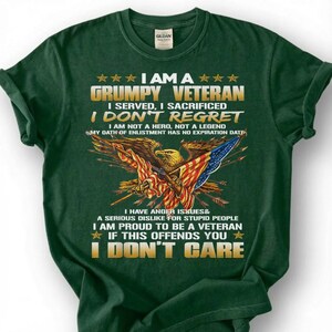 May include: Dark green t-shirt with a graphic featuring an eagle holding a rifle and the American flag. Text includes "I AM A GRUMPY VETERAN" and "I DON'T CARE". The shirt is made of a soft material.