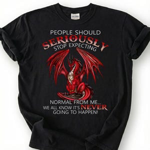 May include: A white ceramic mug with a black handle and the text "But First, Coffee" in a bold, black font. The mug is filled with a dark liquid, likely coffee, and sits on a light-colored surface.