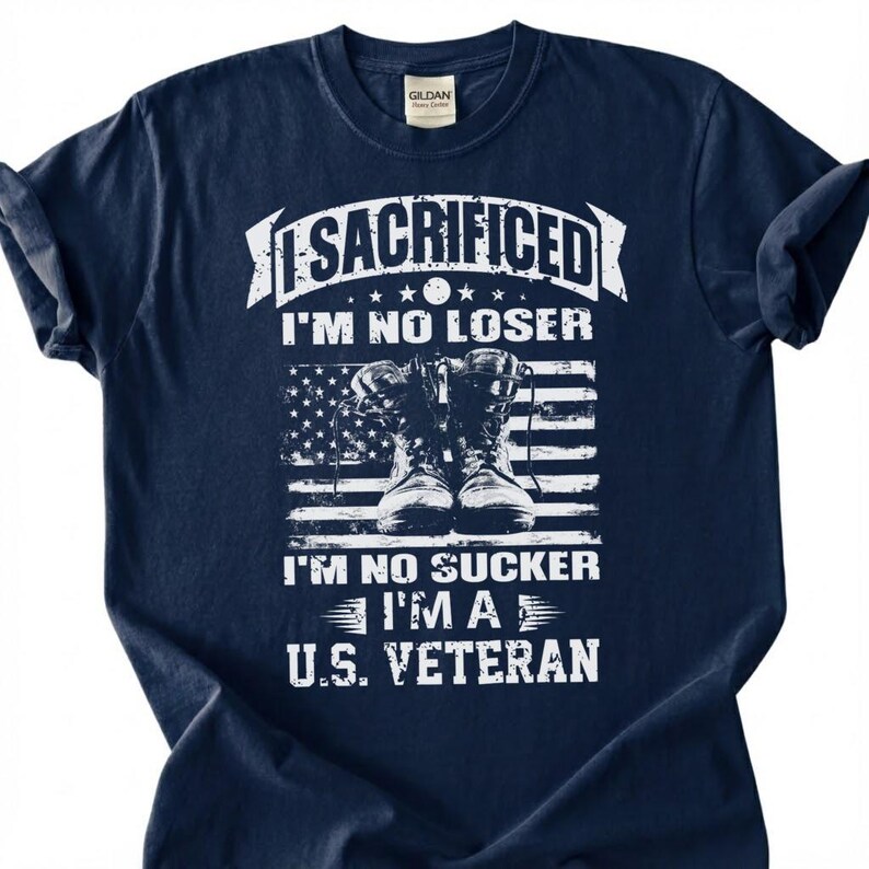 May include: Navy blue t-shirt with white text and a graphic of combat boots in front of an American flag. The text reads "I SACRIFICED I'M NO LOSER I'M NO SUCKER I'M A U.S. VETERAN". The shirt has a crew neck and short sleeves.