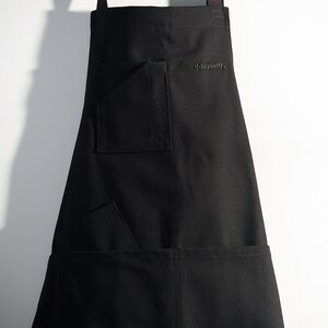 May include: Black apron with two pockets and adjustable straps. The apron has the word "goatboy" embroidered on the front.