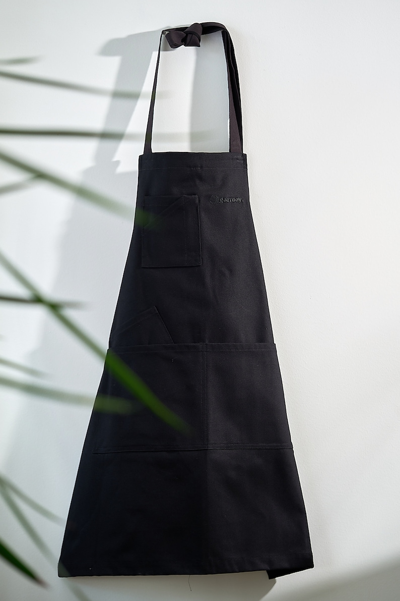May include: A black apron with two pockets and the word "gastronomy" embroidered on the front.