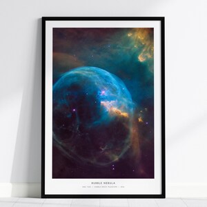 May include: A framed wall art print featuring the Bubble Nebula in deep space. The image displays a large, translucent blue spherical gas cloud against a dark background with golden and purple hues. Text at the bottom reads BUBBLE NEBULA.