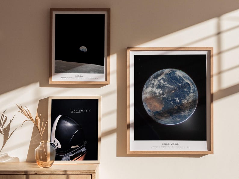 May include: Three framed art prints featuring space-themed imagery. One shows the Earth, another depicts the moon from the lunar surface, and the third displays an astronaut's helmet. The prints are in wooden frames and are displayed on a wall.