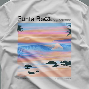 Könnte beinhalten: Ein weißes T-Shirt mit einem Grafikdruck einer Strandszene bei Sonnenuntergang mit Wellen, Palmen und Felsen. Der Text lautet Punta Roca, La Libertad, El Salvador, inklusive der Koordinaten 13 29 9 N / 89 19 12 W.