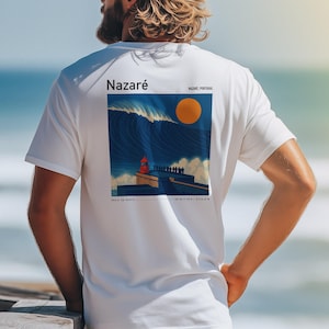 May include: White t-shirt with a graphic print of a large wave crashing on a rocky shore with a lighthouse and the text "Nazaré, Portugal" and "Nazaré" in a larger font.