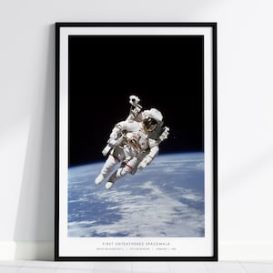 May include: Framed print of an astronaut in a white spacesuit floating in space above Earth. The image shows the astronaut during the first untethered spacewalk. The text at the bottom reads: "FIRST UNTETHERED SPACEWALK".