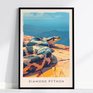 May include: A framed vertical art print featuring a stylized illustration of a diamond python resting on a rocky ledge overlooking a blue mountain landscape. The text DIAMOND PYTHON is printed in black capital letters at the bottom of the print.