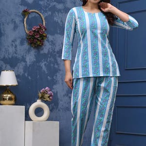 May include: A two-piece pajama set with a blue and white striped pattern. The top has a round neckline and three-quarter sleeves. The pants are straight-legged. The set is made of a lightweight fabric.