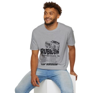 Könnte beinhalten: Ein graues T-Shirt mit einer schwarzen Grafik eines Jeeps und dem Text "Rubicon El Dorado County, CA" sowie einer Liste von Merkmalen. Der Text "Con' Survivor" befindet sich am unteren Rand der Grafik.