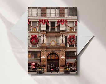 May include: A red brick building with large windows and a large arched entrance. The building is decorated with red and green Christmas wreaths and garlands. The building is labeled "R.H. Macy & Co." and "Macy's".