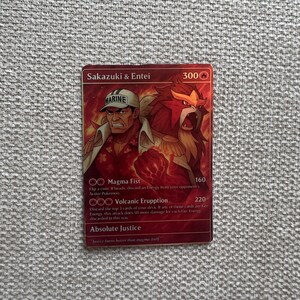 May include: A red Sakazuki & Entei trading card featuring a character in a Marine hat and a fiery beast. The card has text including "Magma Fist" and "Volcanic Eruption".
