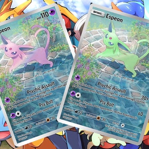 Puede incluir: Dos cartas de intercambio de Pok&eacute;mon con Espeon, un Pok&eacute;mon de tipo Ps&iacute;quico. Las cartas son ambas plateadas y azules con un fondo azul claro. El Pok&eacute;mon se representa en un esquema de color rosa claro y verde. Las cartas presentan el texto "Psychic Assault" y "Psy Bolt".