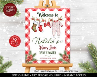 May include: A Christmas-themed baby shower sign on a wooden easel. The sign features a red and white checkered border and illustrations of baby clothes and stockings. The text reads "Welcome to Natalie's Merry Little Baby Shower" and the date.