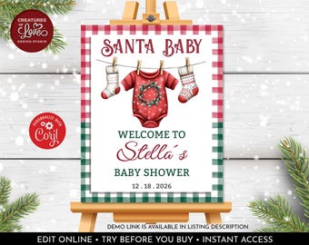 May include: A festive baby shower sign on a wooden easel. The sign features the text "SANTA BABY" above a red onesie and two stockings hanging on a clothesline. The sign reads "WELCOME TO Stella's BABY SHOWER 12.18.2026".