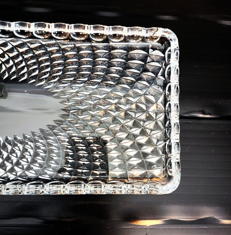 May include: A white ceramic mug with a black handle and the text "But First, Coffee" in a bold, black font. The mug is set against a blurred background, highlighting its clean design.