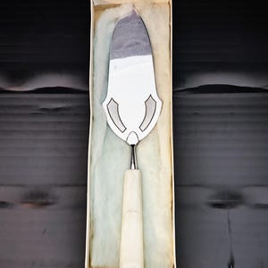 Peut inclure: Un serveur à gâteau en argent avec un manche blanc dans une boîte blanche avec un rembourrage en coton blanc.