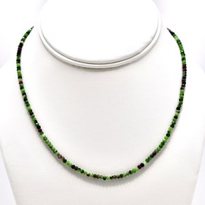 Puede incluir: Un collar de piedras preciosas verdes, rojas y negras con pequeñas cuentas facetadas.