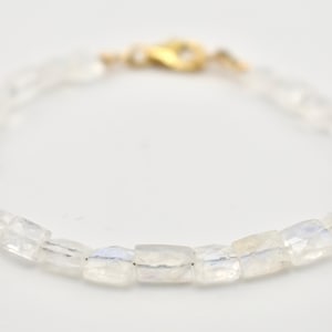 Könnte beinhalten: Ein zartes Armband mit klaren, facettierten rechteckigen Perlen. Die Perlen sind aufgefädelt und das Armband wird mit einem goldfarbenen Verschluss gesichert. Das Gesamtdesign ist schlicht und elegant, geeignet für den täglichen Gebrauch.