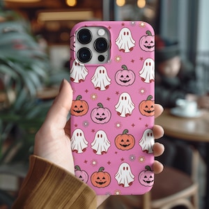 May include: Pink phone case featuring a Halloween-themed pattern. The design includes white ghosts, orange and pink jack-o'-lanterns, small white flowers, and stars. The case is designed for a smartphone.