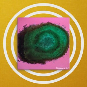 May include: A close-up of a green and black circular pattern on a pink background. The pattern has a dark green center and a lighter green outer ring. The text "Erickson. 24" is in the bottom right corner.