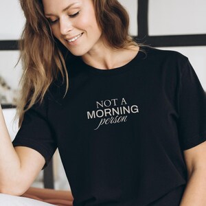 Pu&ograve; includere: Una maglietta nera con la scritta "NOT A MORNING PERSON" in lettere bianche.