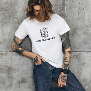 May include: White t-shirt with a black and white illustration of an old fashioned cocktail glass and the text "OLD FASHIONED".