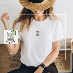 May include: White t-shirt with a small embroidered image of a margarita glass with the text "spicy margs" underneath.