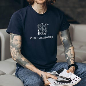 May include: A navy blue t-shirt with a white graphic of a cocktail glass and the text "OLD FASHIONED".