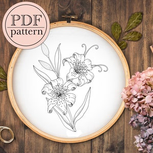 Può includere: Un disegno in bianco e nero di due gigli in un cerchio. I gigli sono dettagliati con petali, steli e foglie. Il cerchio è in legno e ha uno sfondo bianco.