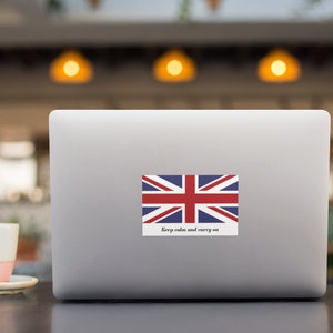 以下が含まれることがあります： ユニオンジャックの旗と「Keep calm and carry on」のテキストが貼られたシルバーのラップトップです。
