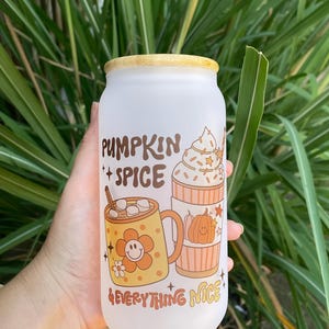 May include: White frosted glass tumbler with a bamboo lid. The tumbler has a graphic design of two mugs with fall-themed drinks and the text "Pumpkin Spice & Everything Nice".