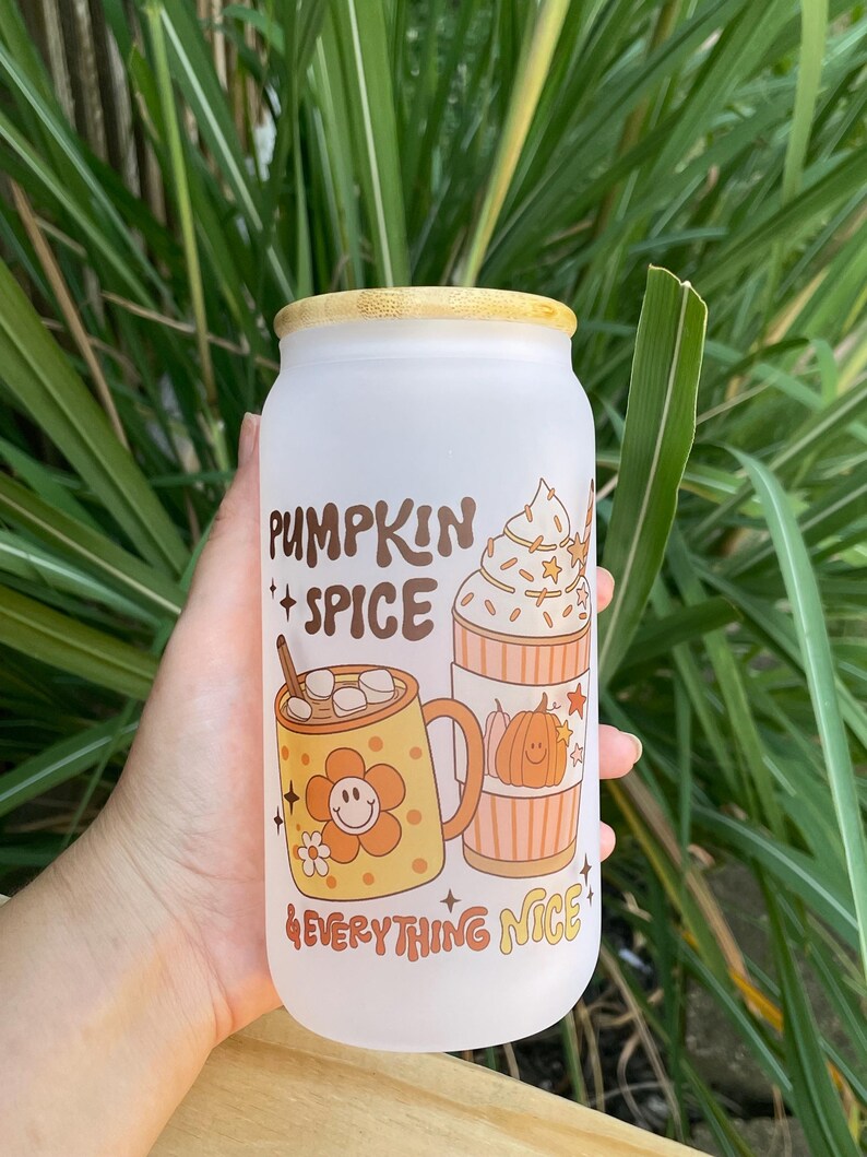 May include: White frosted glass tumbler with a bamboo lid. The tumbler has a graphic design of two mugs with fall-themed drinks and the text "Pumpkin Spice & Everything Nice".