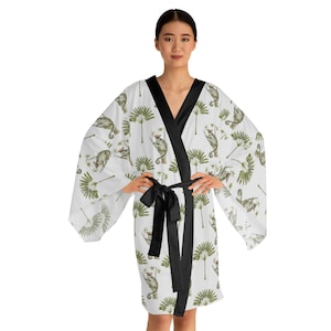 May include: White silk robe with a black satin sash and a print of green palm trees and small animals.