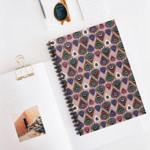 May include: A spiral bound notebook with a brown background and a repeating pattern of colorful peacock feathers. The feathers are arranged in a geometric pattern and have a variety of colors, including blue, green, pink, and brown.