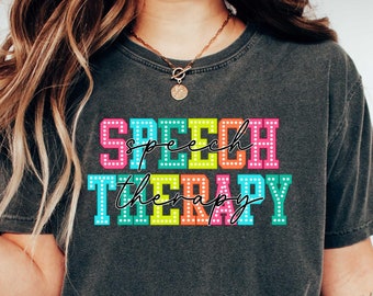 May include: A dark gray t-shirt with the text "speech therapy" in colorful block letters with white polka dots. The letters are outlined in white.